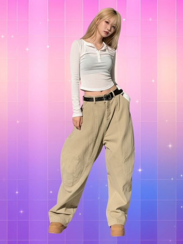 Femme de type coréenne portant le Jean Style Y2K coupe baggy taille basse femme, look rétro avec top blanc sur fond rose violet pixelisé.