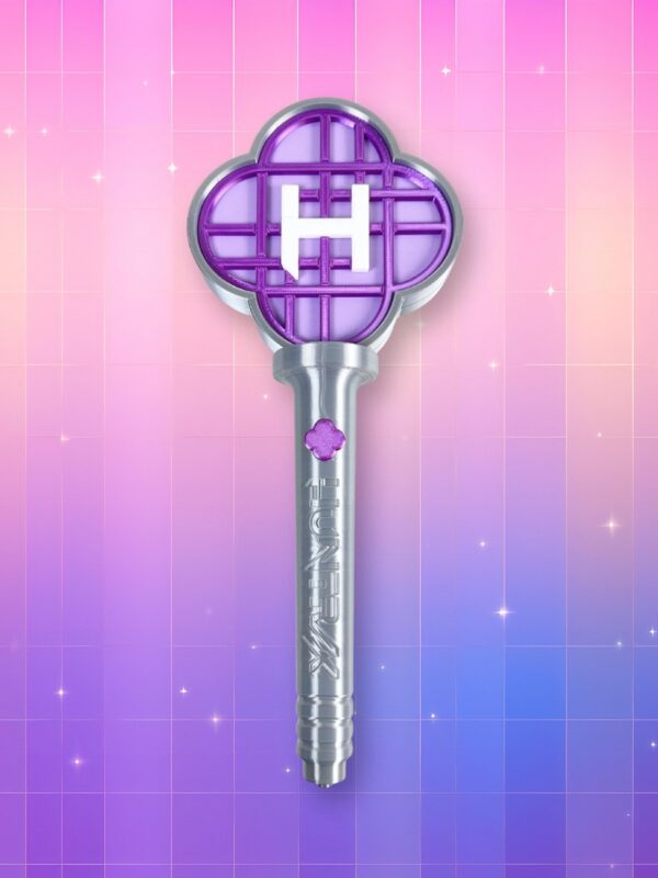 Un jouet Kpop Demon Hunters lightstick Huntrix avec un manche argenté et une tête en forme de trèfle à 4 feuilles contenant un H blanc au milieu, sur un fond artificiel coloré avec un gradient allant du rose au violet.