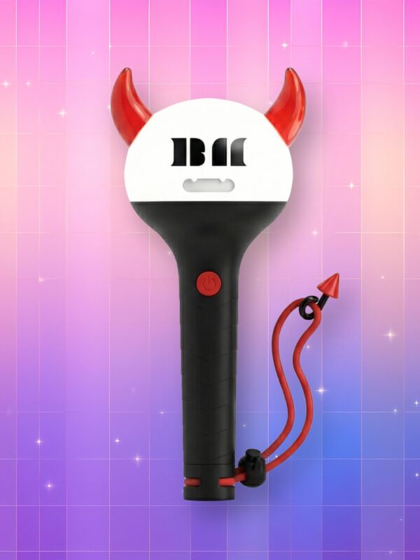 Un lightstick babymonster bluetooth au manche noir, bulbe blanc et des cornes rouges avec le logo du groupe inscrit sur le bulbe, sur un fond artificiel coloré avec un gradient allant du rose au violet.
