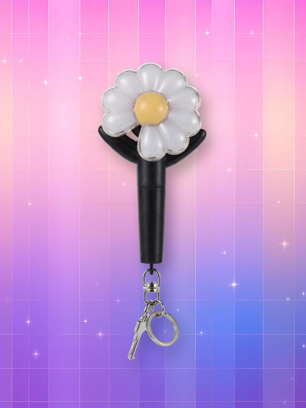 Un Bigbang lightstick G-Dragon version porte-clé avec un manche noir, deux branches latérales noires et un bulbe en forme de fleur à 9 pétales blanches, sur un fond artificiel coloré avec un gradient allant du rose au violet.