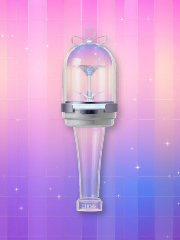 Un Illit lightstick standard quasiment entièrement en plastique transparent, présentant un manche translucide, un anneau en plastique opaque et un dôme complètement translucide avec une fleur à l'intérieur, sur un fond artificiel coloré avec un gradient allant du rose au violet.