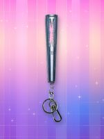 Un lightstick Le Sserafim version porte-clés, de forme cylindrique avec une forme abstraite à l'image de leur logo découpée dans la partie supérieure du lightstick, diffusant de la lumière, sur un fond artificiel coloré avec un gradient allant du rose au violet.