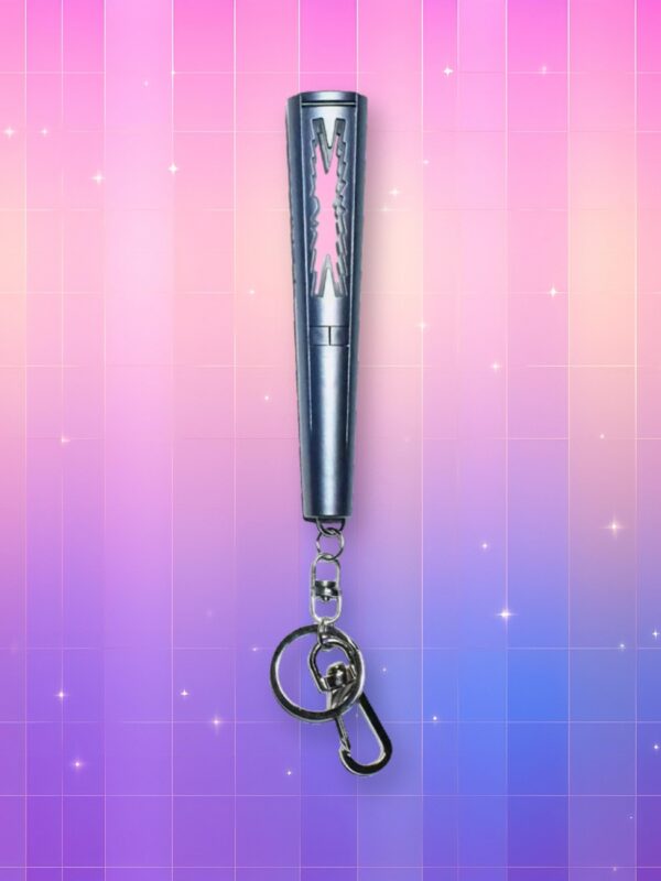 Un lightstick Le Sserafim version porte-clés, de forme cylindrique avec une forme abstraite à l'image de leur logo découpée dans la partie supérieure du lightstick, diffusant de la lumière, sur un fond artificiel coloré avec un gradient allant du rose au violet.