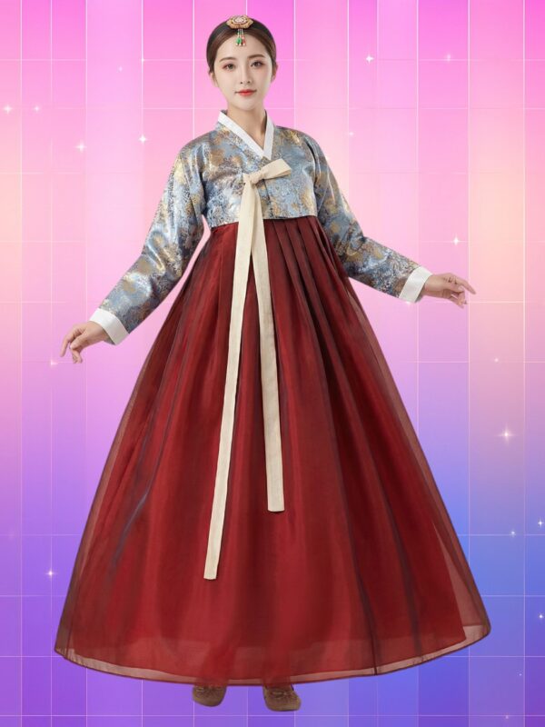 Femme asiatique en hanbok traditionnel avec un jeogori bleu brodé à reflets dorés, un otgoreum crème noué au centre et une chima lie-de-vin ample et vaporeuse, sur fond rose-violet lumineux.