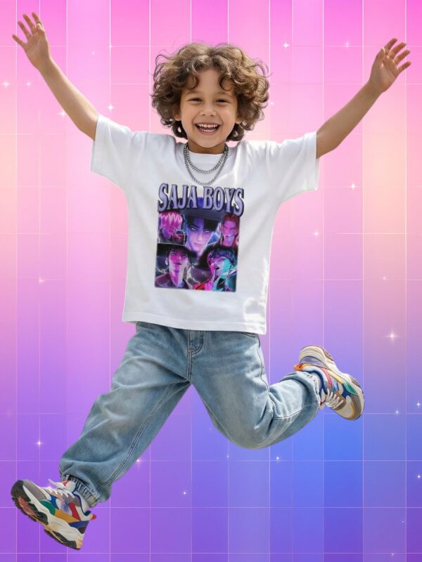 Un garçon saute de joie en portant le t-shirt K-Pop garçon SAJA BOYS blanc, décoré de visages stylisés façon manga, sur fond rose et violet étoilé.