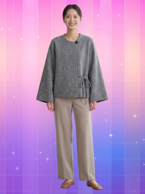 Femme souriante portant une veste kimono femme laine feutrée coréenne grise avec pantalon beige et chaussures marron, sur fond rose-violet dégradé étoilé.