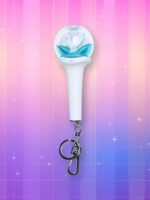 Un lightstick Nmixx Mixxtick version porte-clés blanc et bleu avec un bulbe représentant une baleine dans un océan bleu, sur un fond artificiel coloré avec un gradient allant du rose au violet.
