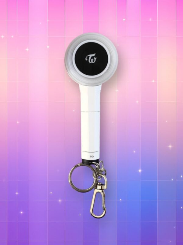 Un lightstick Twice version porte-clés preésantant un manche blanc avec le nom du groupe dessus et une tête en forme de disque au centre noir avec le logo du groupe, sur un fond artificiel coloré avec un gradient allant du rose au violet.
