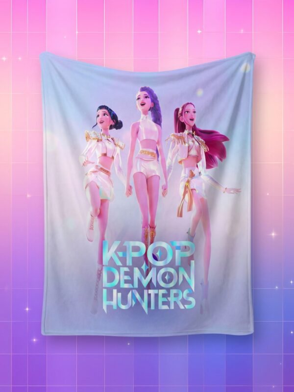 Un plaid léger Huntrix représentant les membres du groupe dans leurs tenues de concert blanches à reflets holographiques, sur un fond artificiel coloré avec un gradient allant du rose au violet.