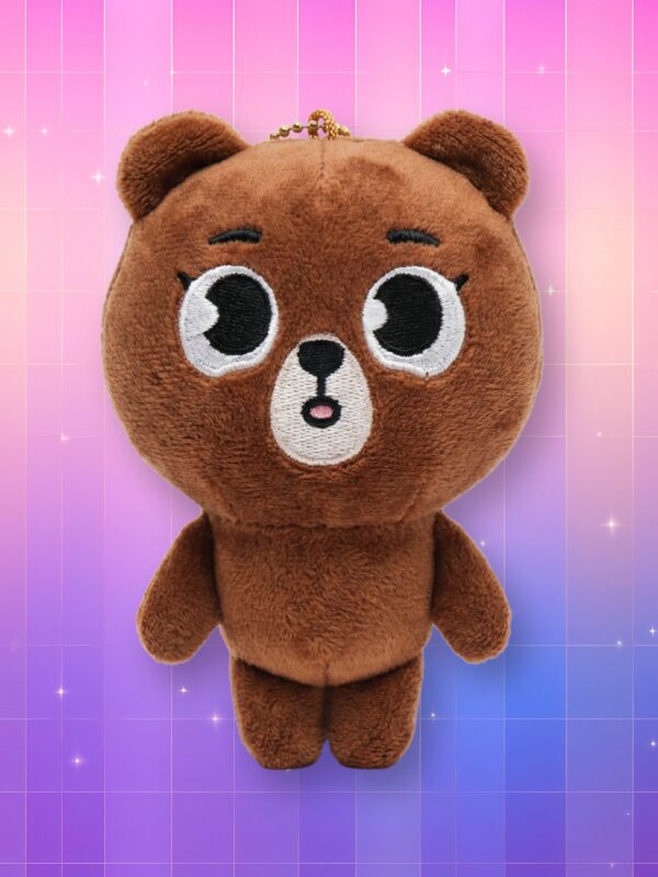 Une peluche porte-clés Day6 Denimalz - Bang représentant un ours brun avec de grands yeux sur un fond dégradé rose et violet.
