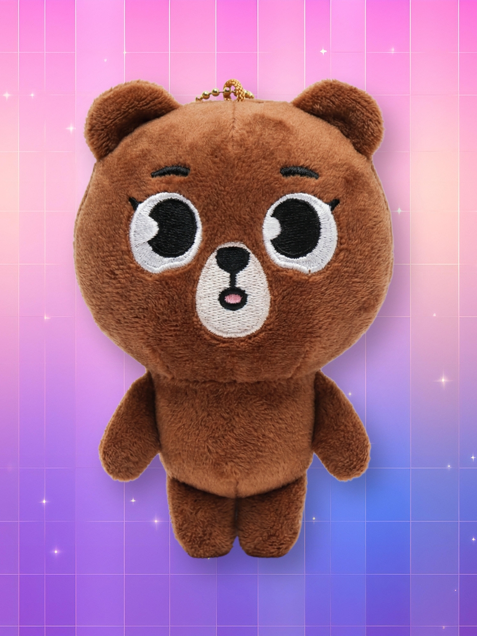 Une peluche porte-clés Day6 Denimalz - Bang représentant un ours brun avec de grands yeux sur un fond dégradé rose et violet.