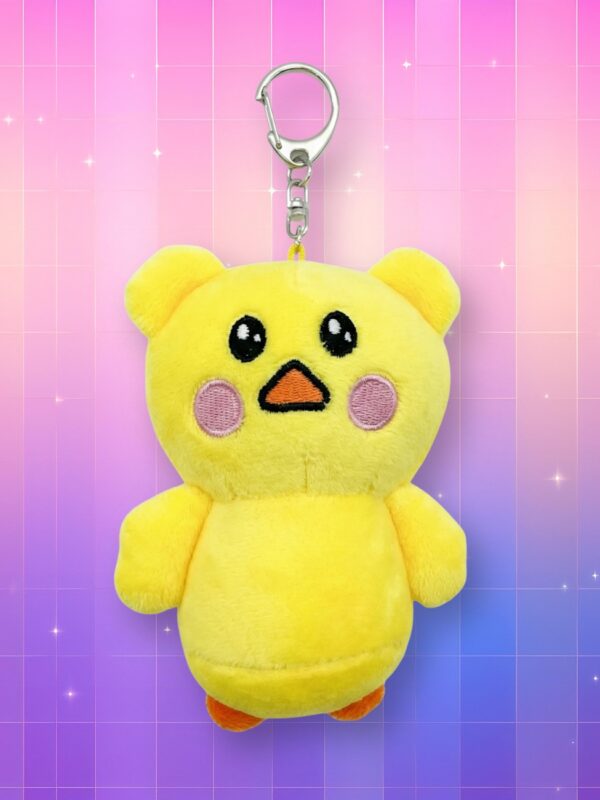 Une petite Peluche porte-clés Le Sserafim - Hongppippi en forme de poussin jaune tout doux avec des joues roses, suspendue par une attache métallique sur un fond graphique dégradé rose et violet aux reflets étoilés.