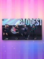 Un tapis de souris kpop KDA The Baddest illustrant les quatre chanteuses du groupe en tenues sombres et stylées sur un fond noir, surmonté d'une bannière holographique avec le titre, présenté sur un arrière-plan quadrillé aux couleurs dégradées rose et violet avec des étoiles.
