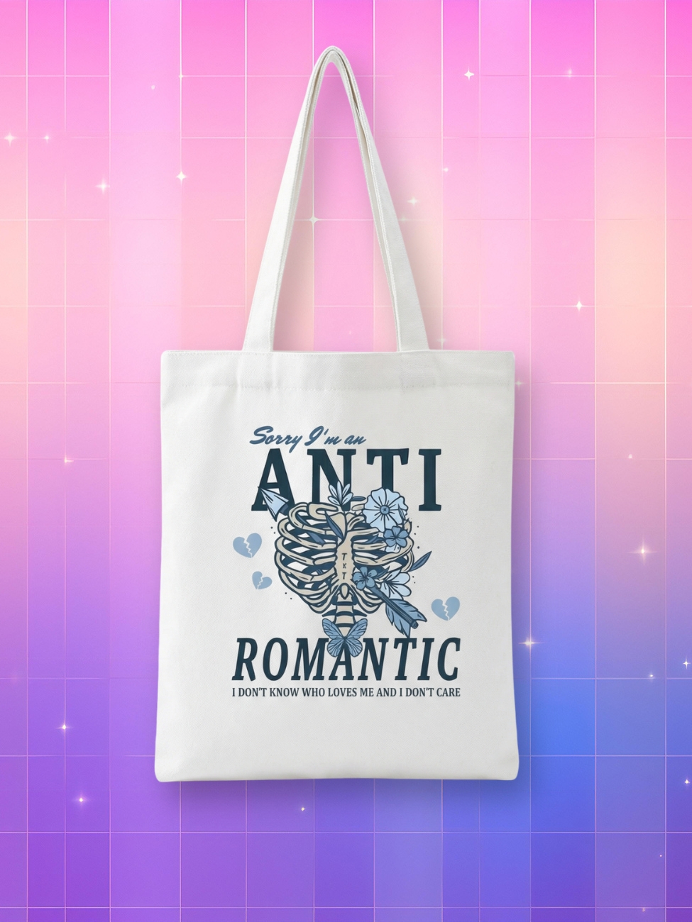 Un Tote bag Kpop TXT Anti Romantic blanc avec un dessin de cage thoracique et des fleurs bleues sur un fond coloré rose et violet.