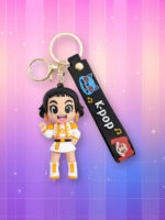 Un porte-clés kawaii Kpop Demon Hunters Zoey la représentant dans sa tenue de concert noire, blanche et dorée avec un mousqueton doré et une sangle noire avec écrit "kpop" dessus, sur un fond artificiel coloré avec un gradient allant du rose au violet.