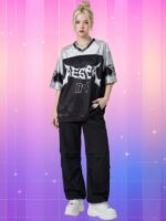 Une jeune femme blonde portant un maillot kpop Aespa style foot US large, aux couleurs noir et argenté avec des écritures blanches, accompagné d'un pantalon noir ample et de baskets blanches, sur un fond quadrillé aux tons dégradés de rose et violet.