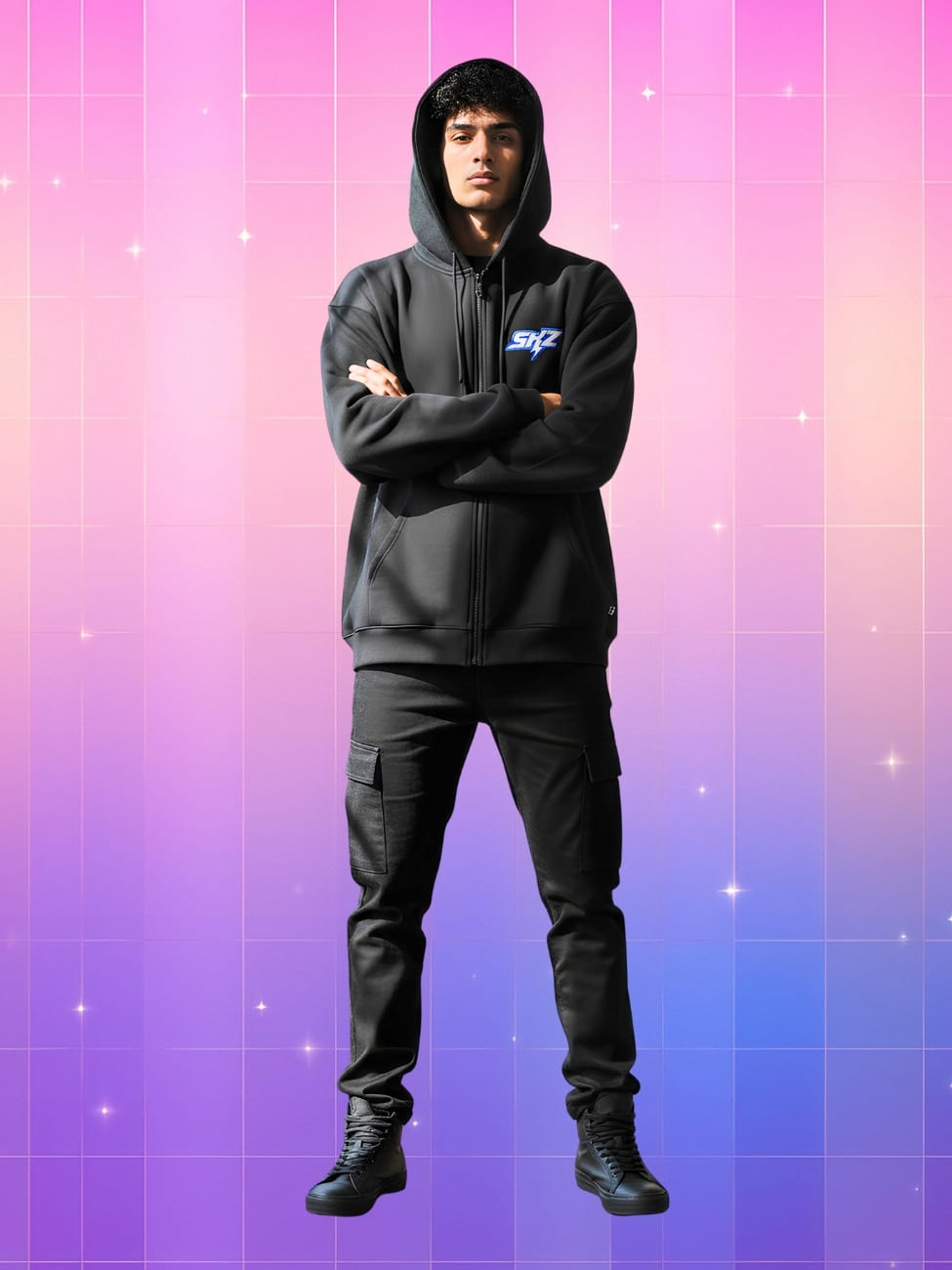 Sweat Kpop à capuche Bang Chan SKZ porté par un homme métisse avec la capuche sur la tête et les bras croisés. Il porte un pantalon noir. Sur fond dégradé de rose à violet.