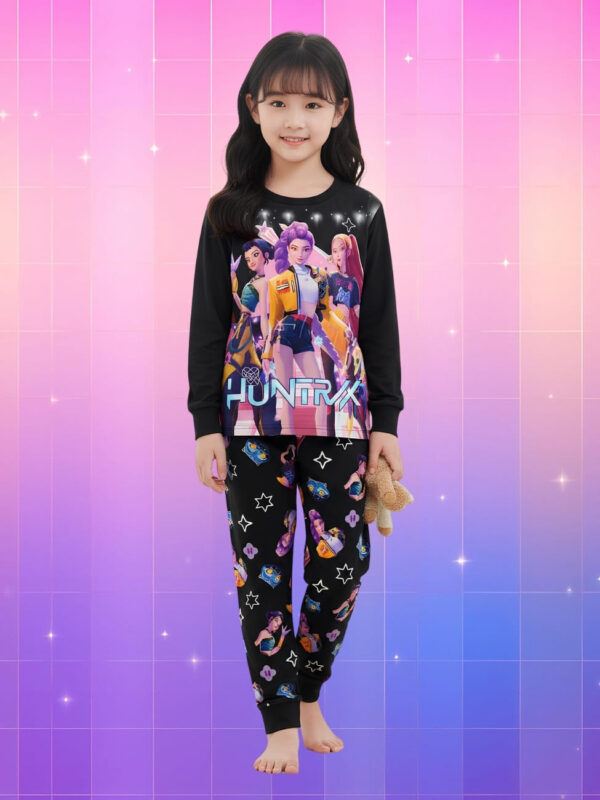 Pyjama Kpop Demon Hunters Huntrix pour fille de couleur noire à manches longues et pantalon porté par une fille de type asiatique sur fond dégradé de rose à violet. Le pyjama montre un gros motif avec les héroïnes Huntrix sur le haut et plusieurs motifs sur le pantalon.