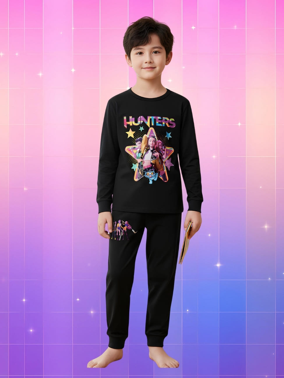 Pyjama Kpop Demon Hunters long pour enfant de couleur noire avec un gros motif sur le haut et un petit sur la cuisse droite. Porté par un jeune garçon de type asiatique sur fond dégradé de rose à violet.