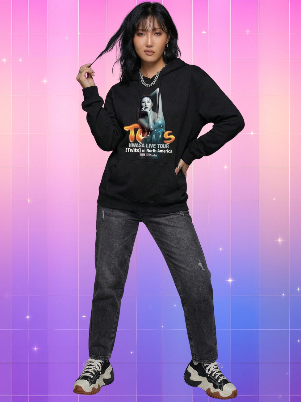 Une jeune femme portant un pull kpop Hwasa tournée Twits noir avec une illustration de la chanteuse sur le devant, associée à un jean gris foncé, devant un background quadrillé aux couleurs dégradées rose, violet et bleu avec des petites étoiles étincelantes.