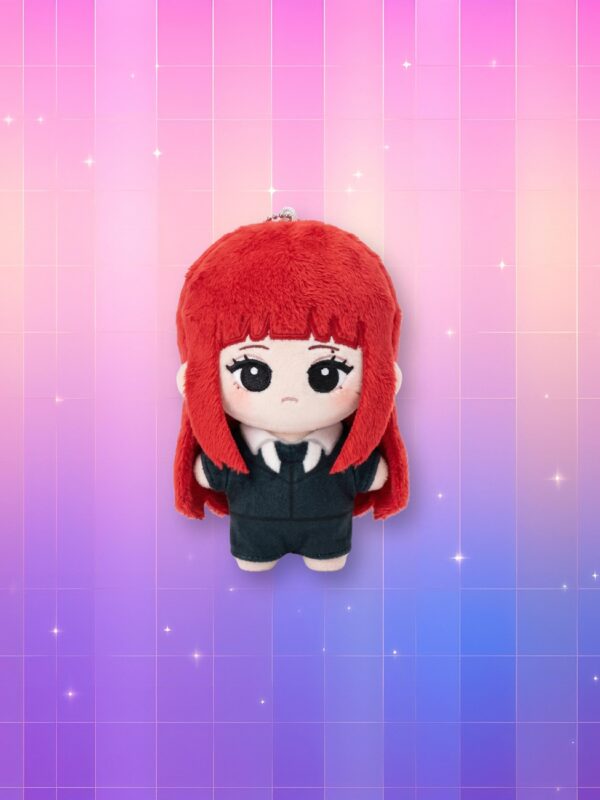 Une petite peluche porte-clés kpop Kim Jennie Ruby avec des cheveux rouge vif et un costume noir, présentée devant un fond quadrillé aux reflets dégradés allant du rose au violet avec de petites étoiles scintillantes.
