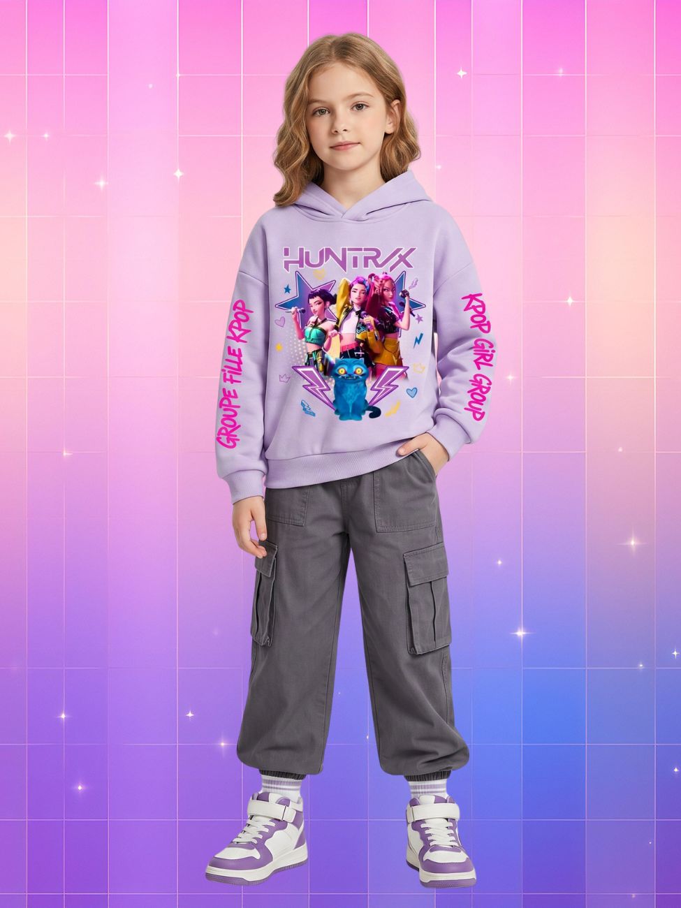 Une jeune fille porte un pull à capuche kpop enfant Huntrix et Derpy violet, avec un grand dessin coloré au centre, sur un fond rose et violet en dégradé.