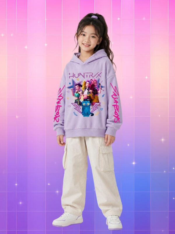 Une jeune fille porte un pull à capuche kpop enfant Huntrix et Derpy violet, avec un grand dessin coloré au centre, sur un fond rose et violet en dégradé.